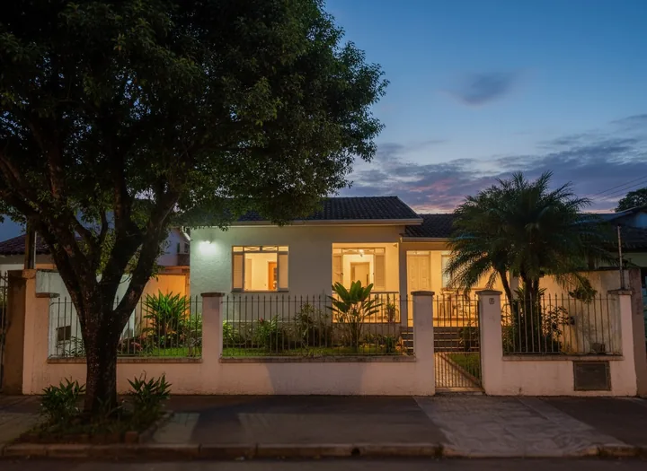 Casa brasileira com as luzes acesas ao entardecer